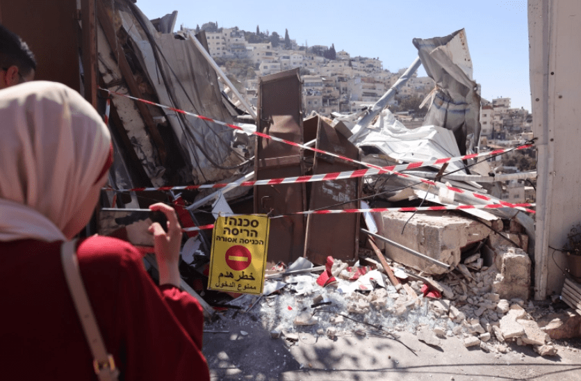 Palestinian residents stand by the rubble of a shop demolished by Israeli authorities in the occupied East Jerusalem neighbourhood of Silwan [Ahmad Gharabil/AFP]