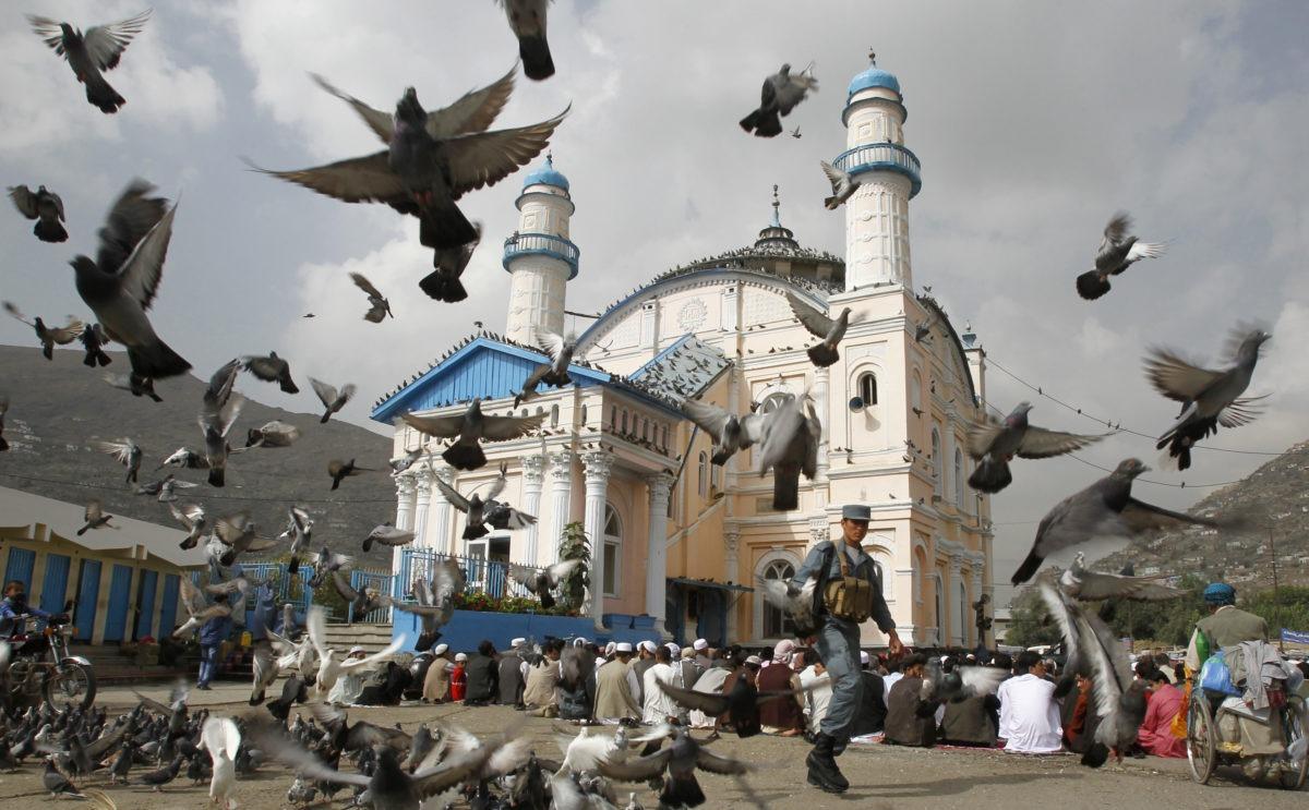 Left: Pigeons fly as a policeman guards residents praying outside the Shah-e Doh Shamshira mosque during the first day of the Muslim holiday of Eid-al-Fitr in Kabul on Aug. 30, 2011. Photo by Erik de Castro/Reuters