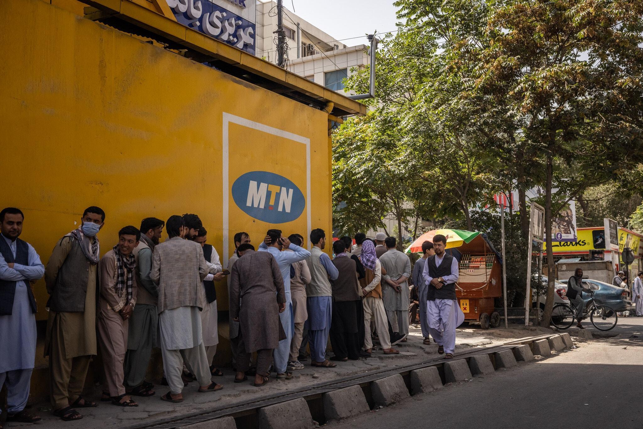 People stood in line outside Azizi bank in Kabul on Sunday, the first day banks reopened in Afghanistan’s capital.Credit...Jim Huylebroek for The New York Times