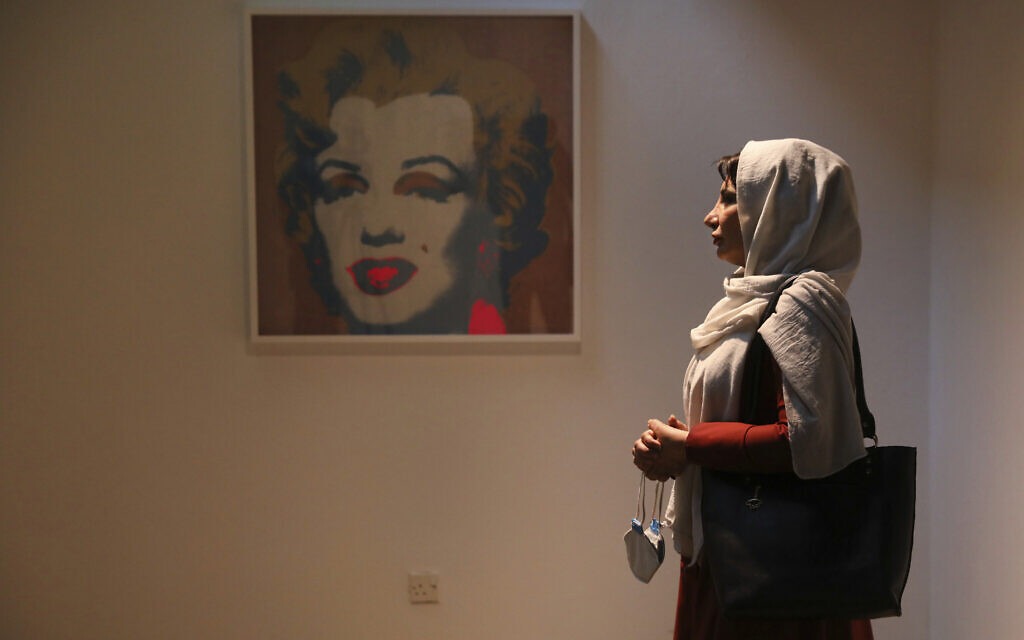 Fatemeh Rezaei, a retired teacher, stands next to a Marilyn Monroe portrait by American artist Andy Warhol at Tehran Museum of Contemporary Art in Tehran, Iran, on October 19, 2021. (AP Photo/Vahid Salemi)