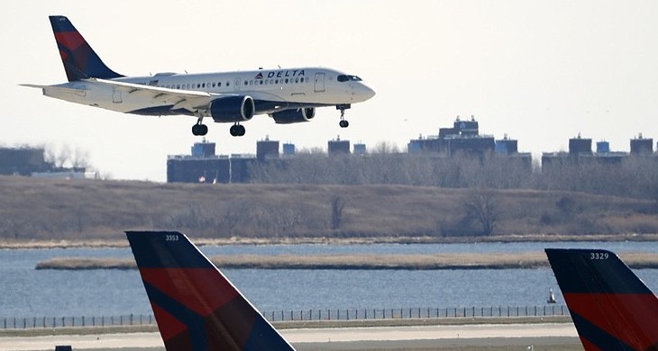 A Delta Airlines jet lands at John F. Kennedy International Airport as two other Delta planes are shown at the terminal
