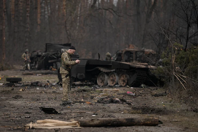 A Ukrainian serviceman takes a photo of a dead Russian soldier after Ukrainian forces overran a Russian position outside Kyiv on March 31. (Vadim Ghirda/AP)