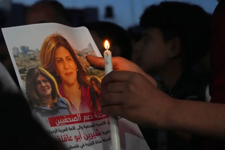 A Palestinian holds a lit candle and a picture of Abu Akleh in Gaza City [File: Adel Hana/AP]