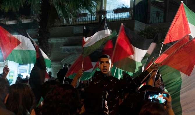 Protesters wave Palestinian flags outside of the family home of veteran journalist Shireen Abu Akleh. (AP)